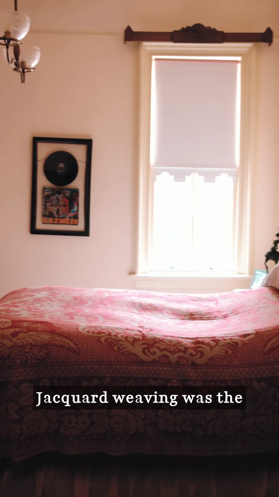 A pink bedroom with a jacquard-woven bedspread beside a sunlit window